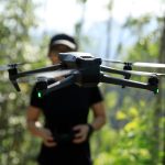 People remote control a flying drone in summer forest