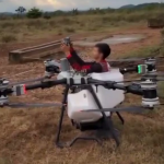 Un homme assis sur un drone agricole DJI en vol au-dessus d'un terrain sec